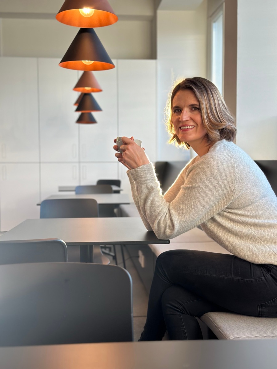 Angela Bauer, Gründerin von Hungry, sitzt mit einer Tasse Kaffee an einem Tisch